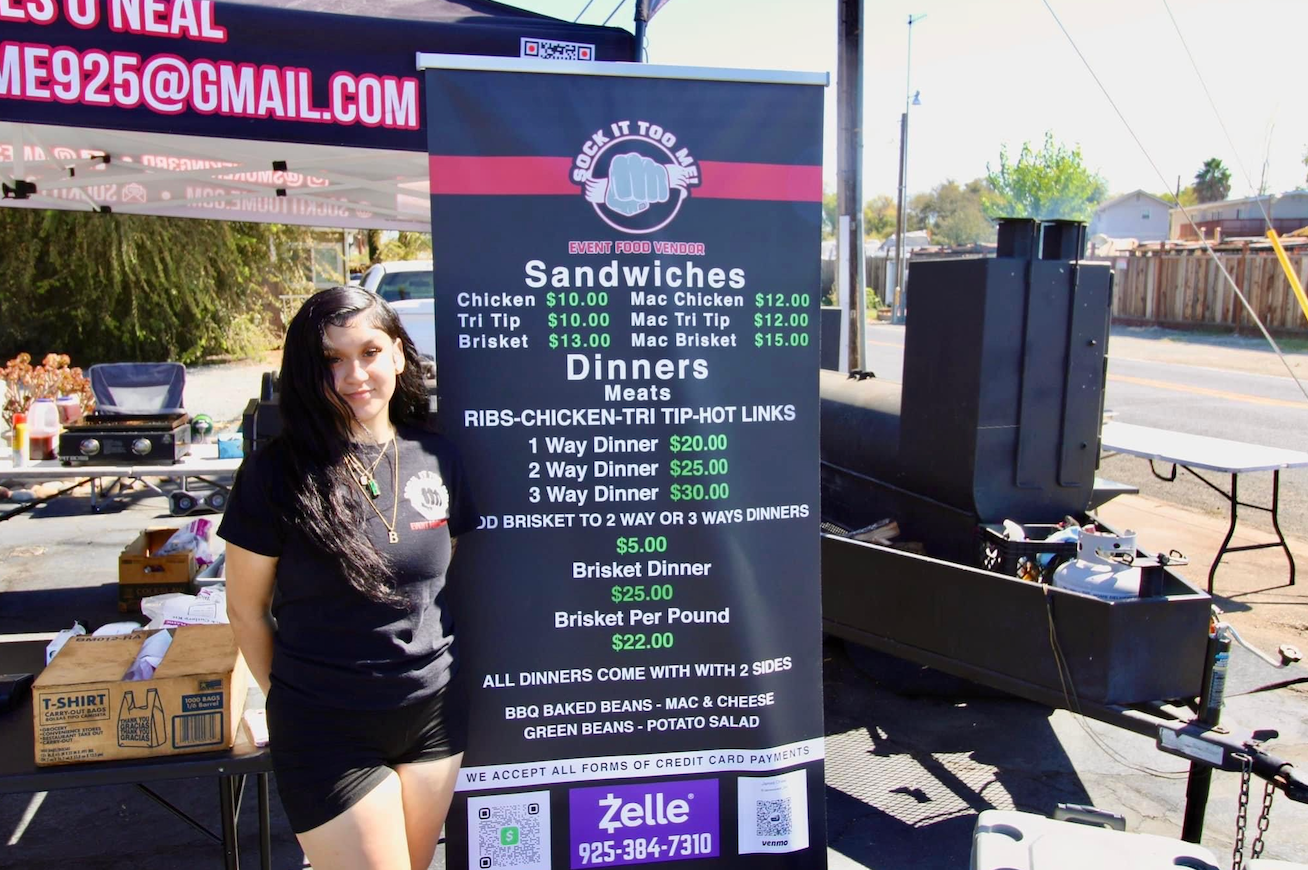 A woman is standing in front of a sign that says sandwiches and dinners