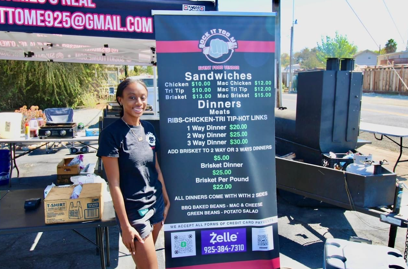A woman is standing in front of a sign that says sandwiches and dinners