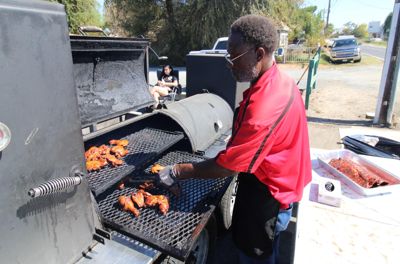 A man in a red shirt is cooking food on a grill