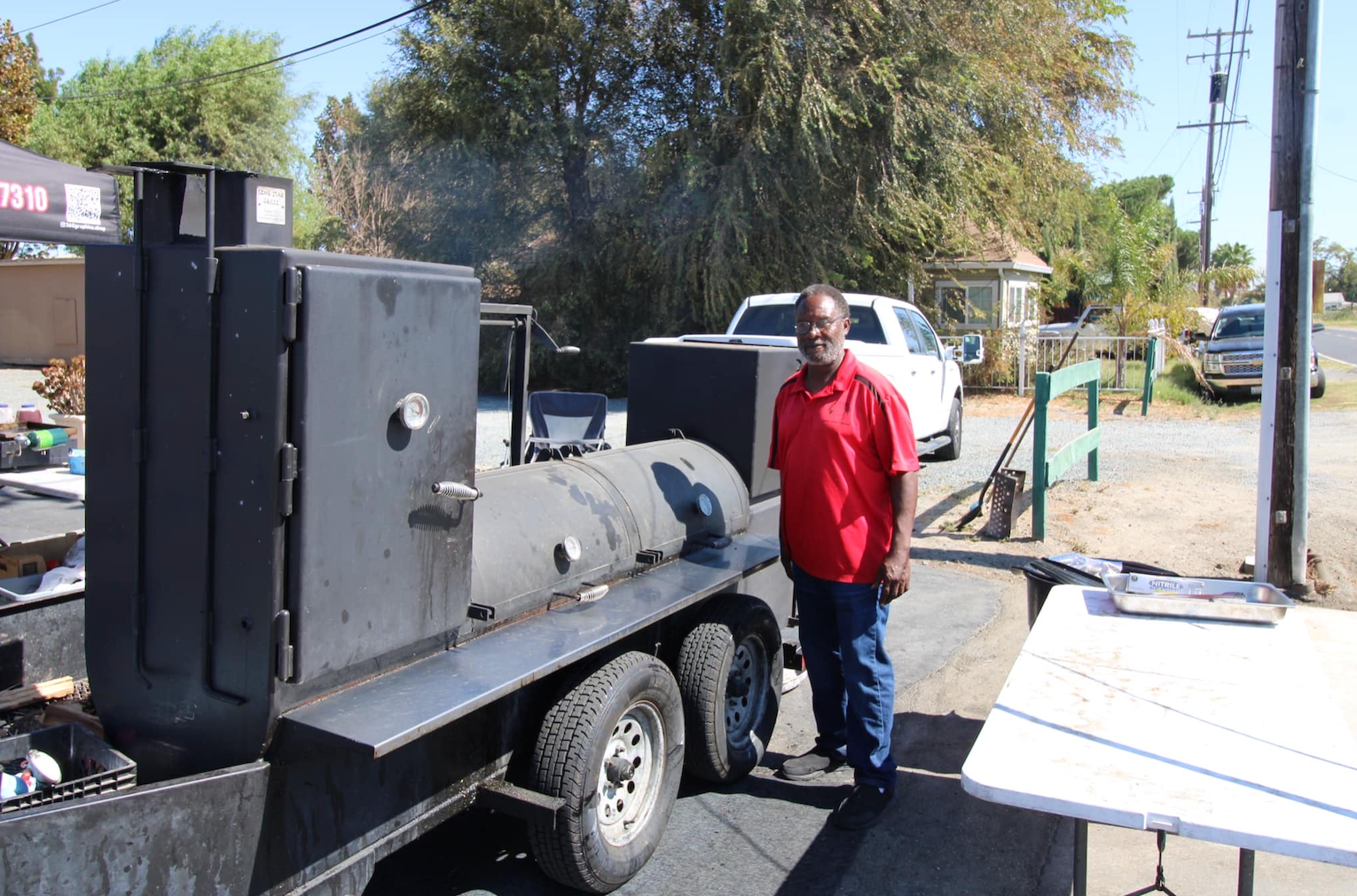 A man in a red shirt is standing in front of a trailer