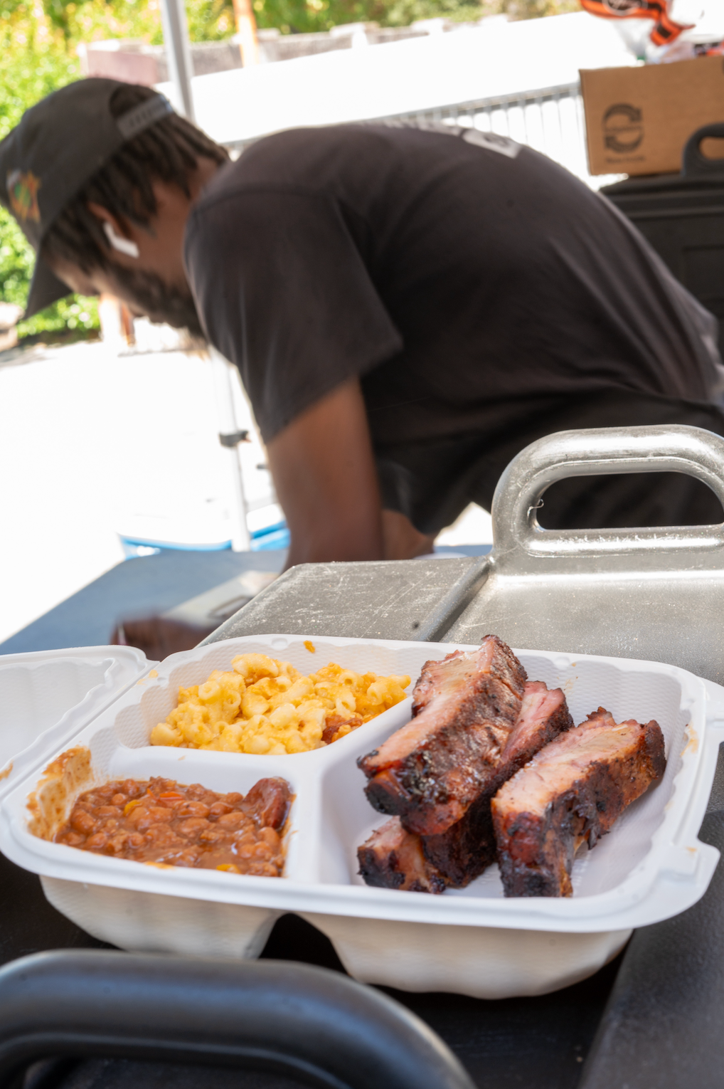 A man in a black shirt is leaning over a tray of food