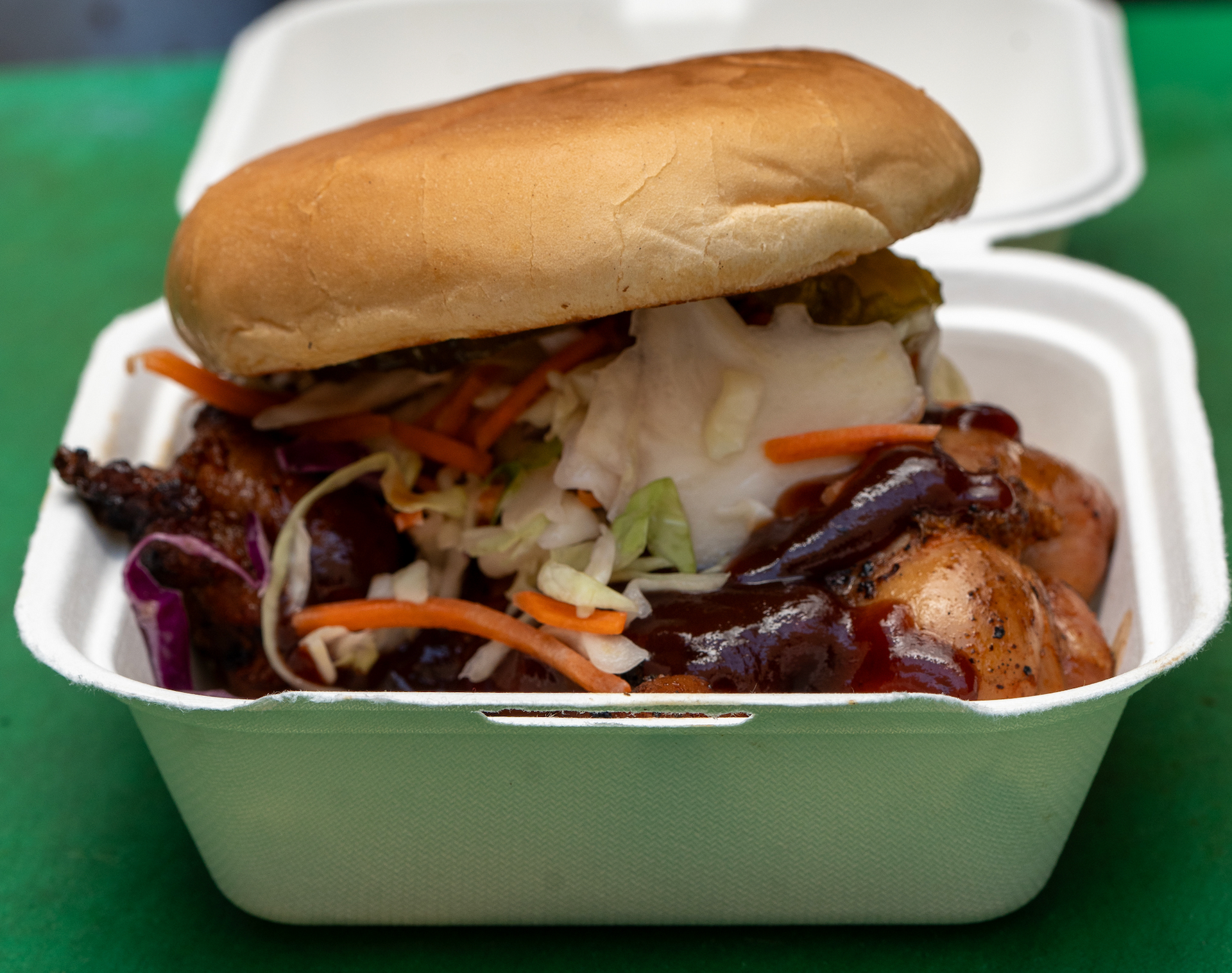 A sandwich is in a styrofoam container on a table.