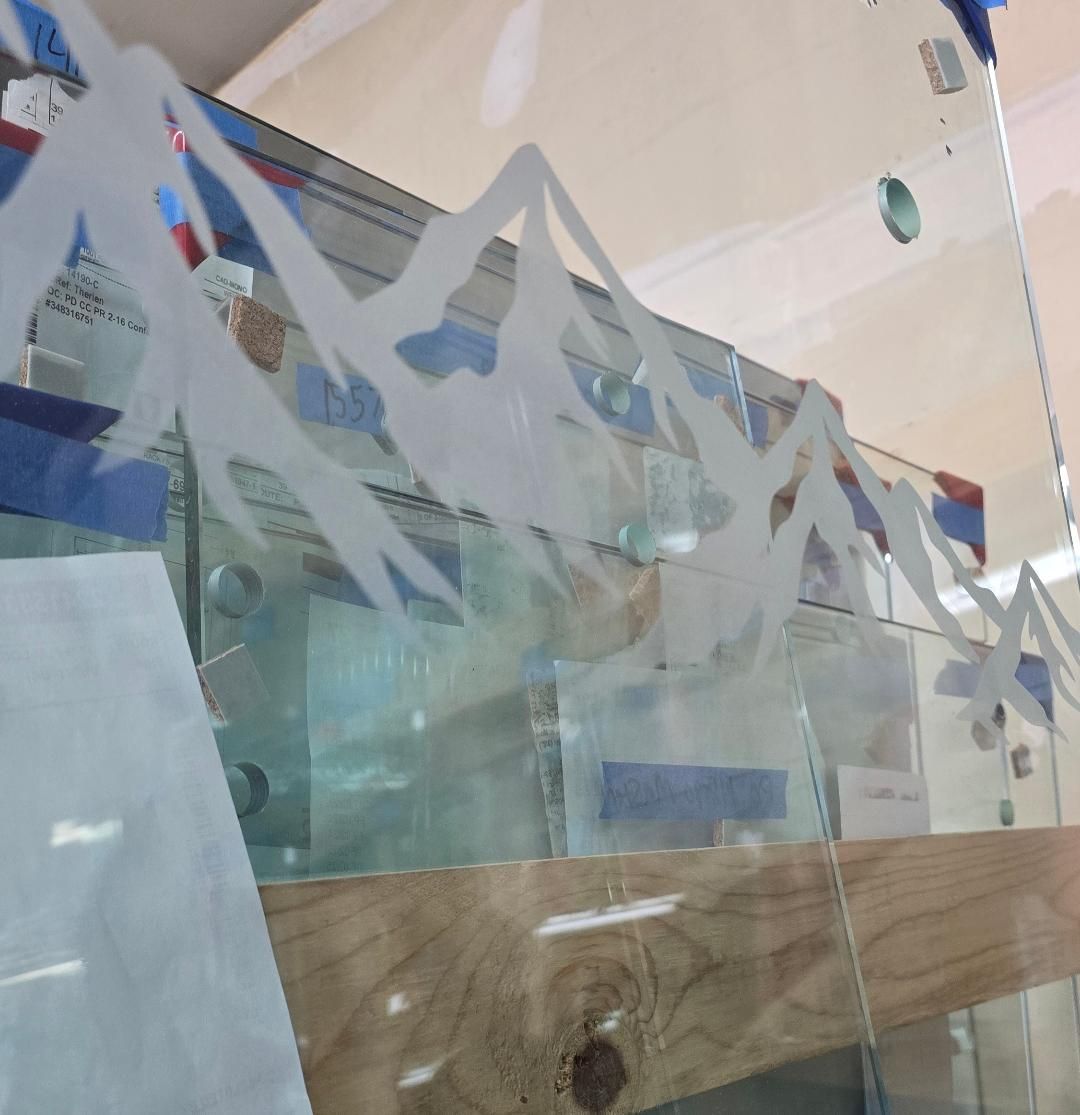 Clear plastic safety barrier with blue tape and a wooden rail in an indoor setting