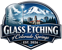Logo for Glass Etching of Colorado Springs, featuring a mountain, cityscape, eagle, and pine tree on a blue shield.