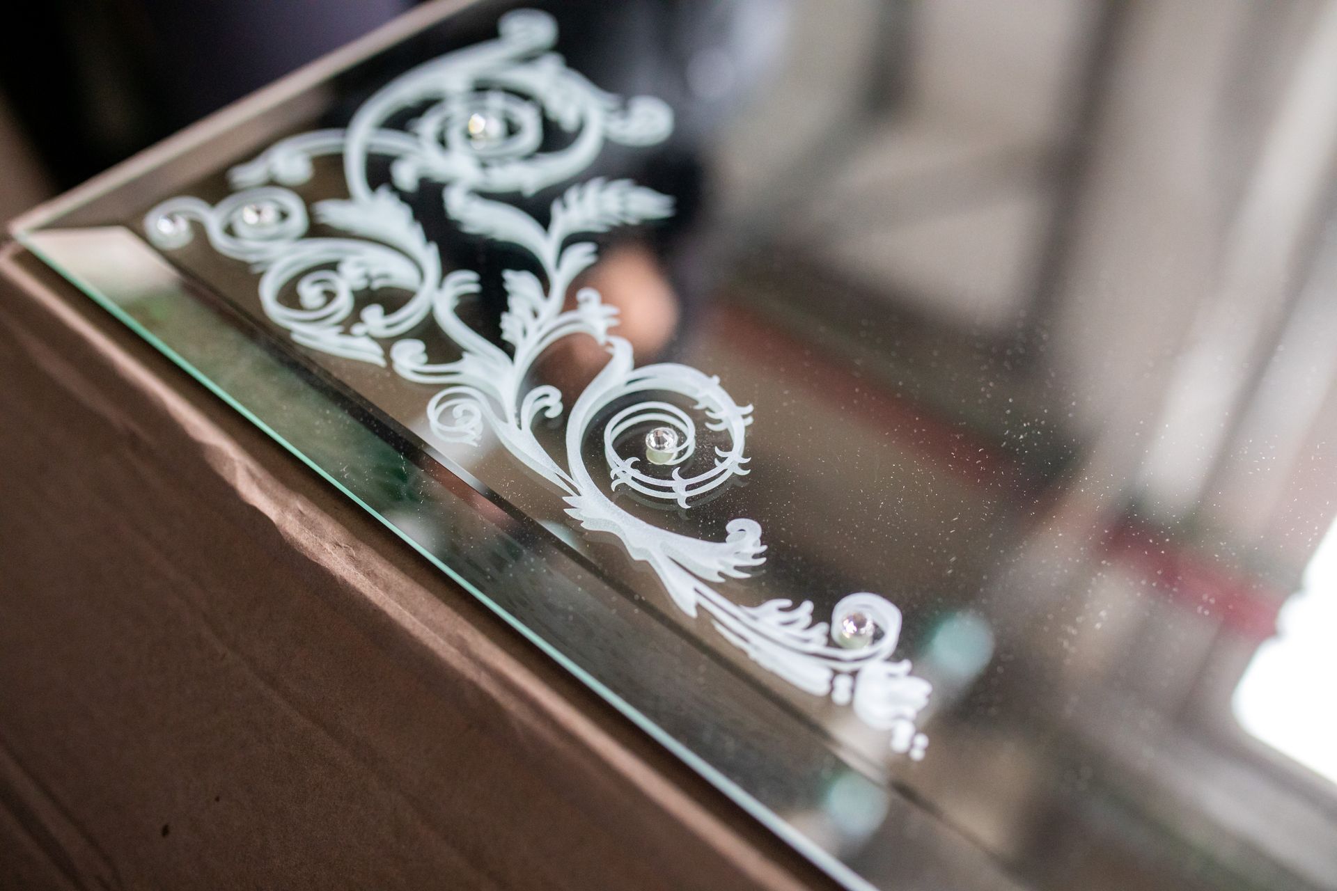 Decorative white floral etching on a glass surface near a wooden frame