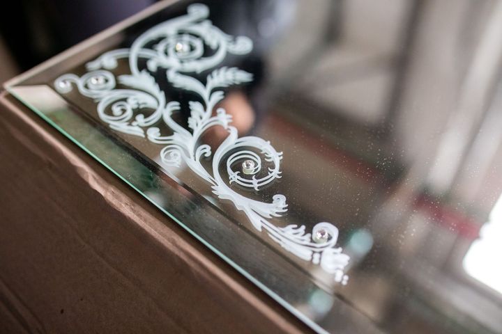 Decorative white floral etching on a glass surface near a wooden frame