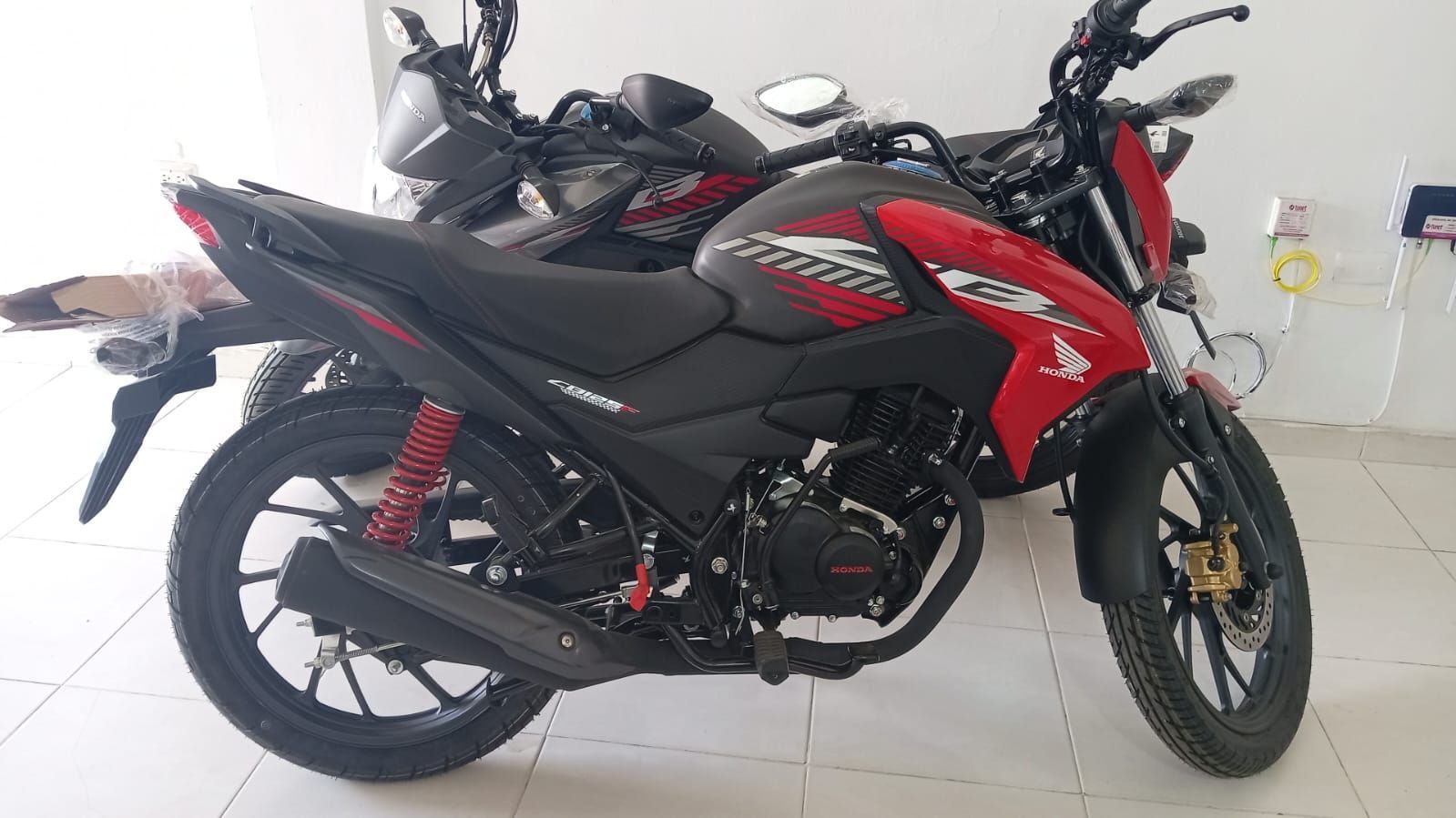 Motocicleta Honda roja y negra estacionada dentro de una sala de exposición.