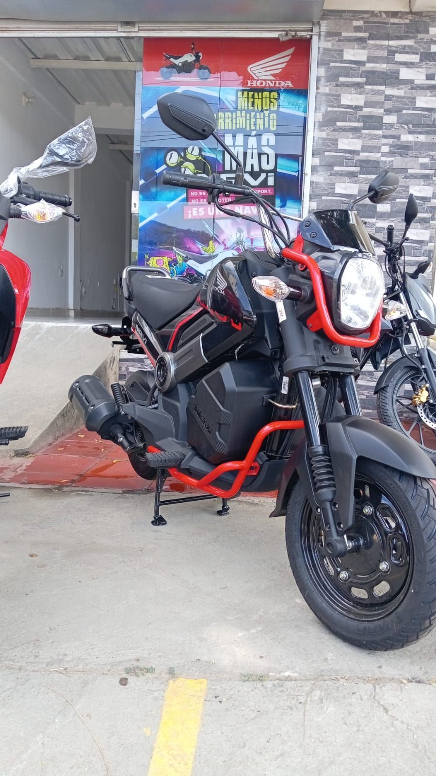 Motocicleta Honda negra y roja estacionada afuera de una tienda.