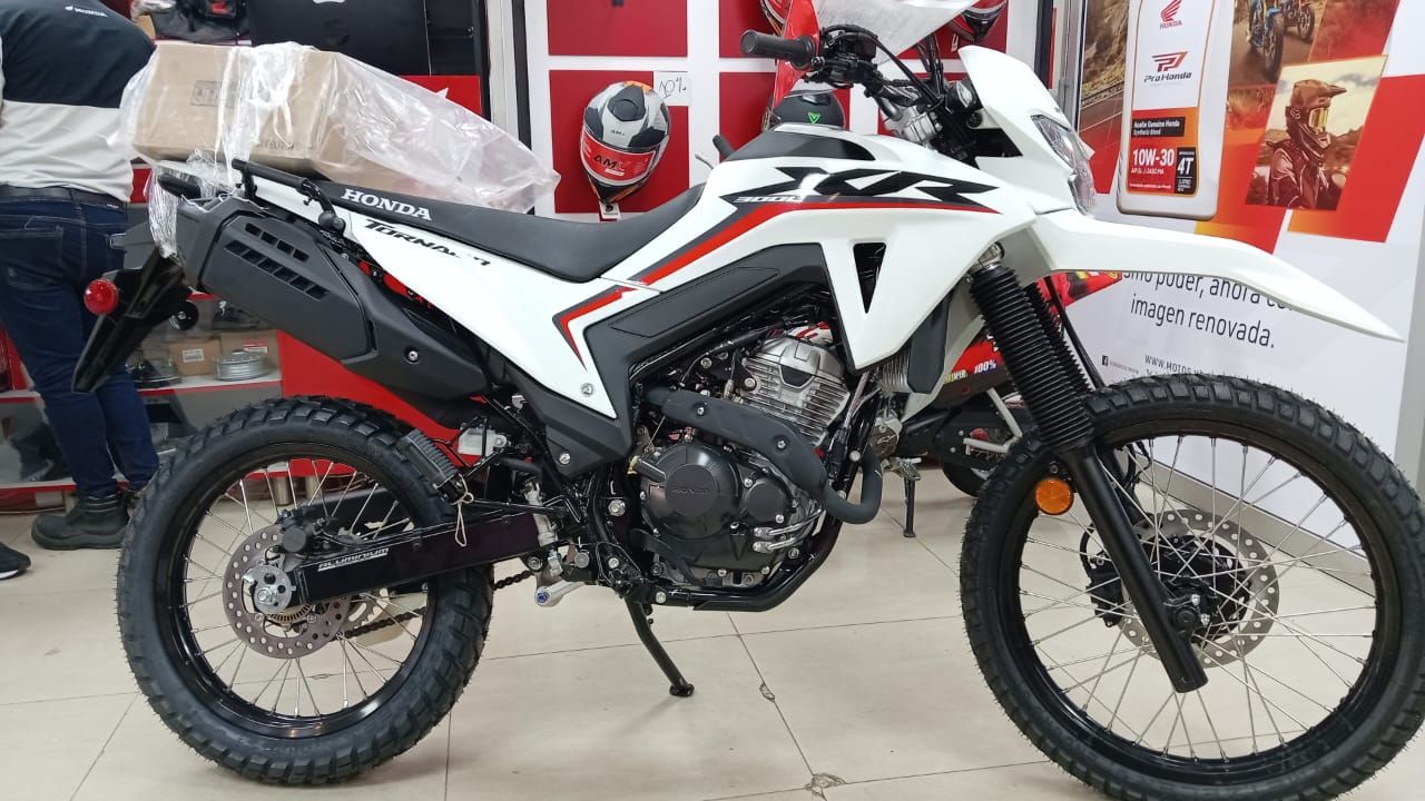 Motocicleta Honda dual-sport blanca y roja en una sala de exposición.