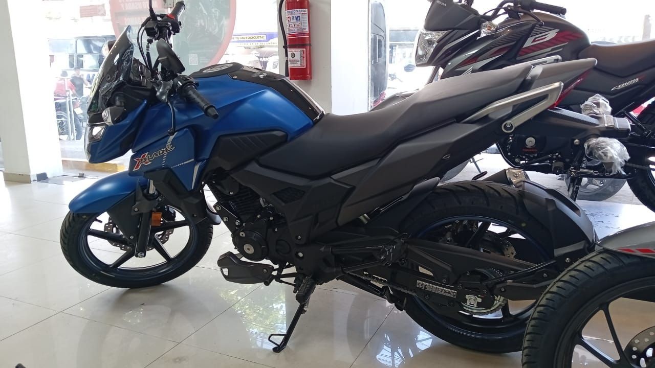 Motocicleta Honda azul en exhibición en una sala de exposición, con asiento y neumáticos negros.