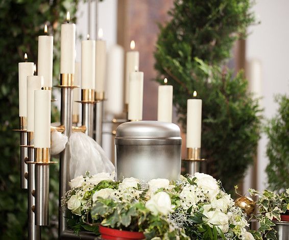 A urn is surrounded by flowers and candles at a funeral.