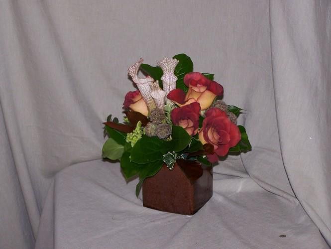 A wooden vase filled with flowers sits on a table