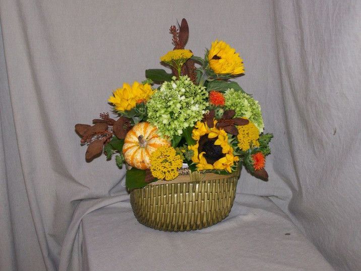 A basket filled with yellow and green flowers and a pumpkin