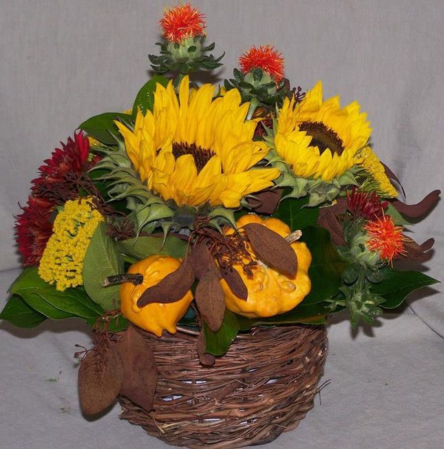 A wicker basket filled with sunflowers and pumpkins