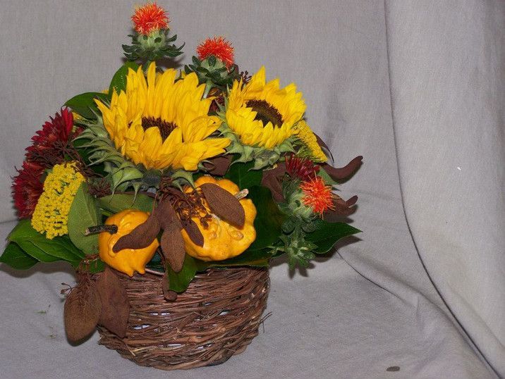 A wicker basket filled with sunflowers and pumpkins