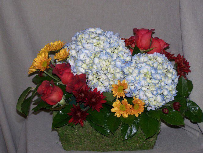A bouquet of flowers including blue hydrangea and red roses