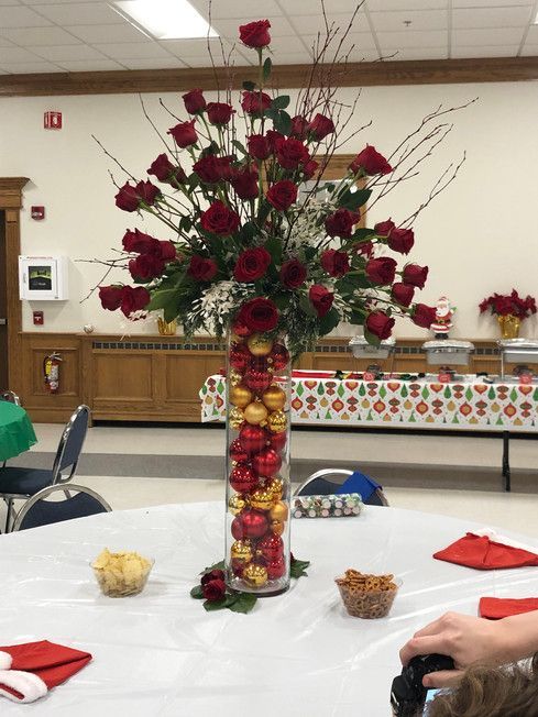 A vase filled with red roses and christmas ornaments on a table