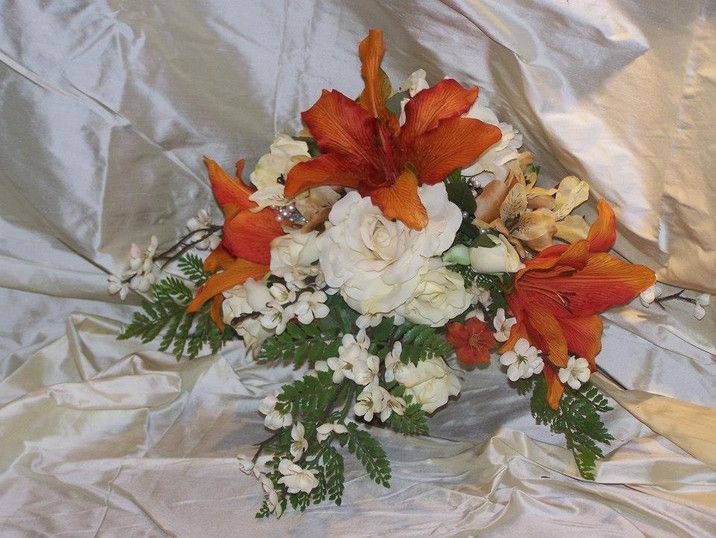 A bouquet of orange and white flowers on a silver cloth