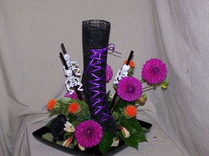 A black vase filled with purple flowers and skeletons