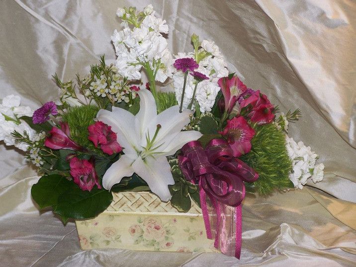 A white lily is surrounded by pink and white flowers