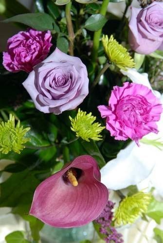 A close up of a bouquet of purple and pink flowers in a vase.