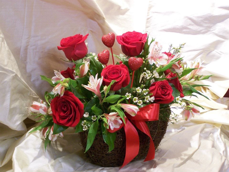 A vase filled with red roses and other flowers