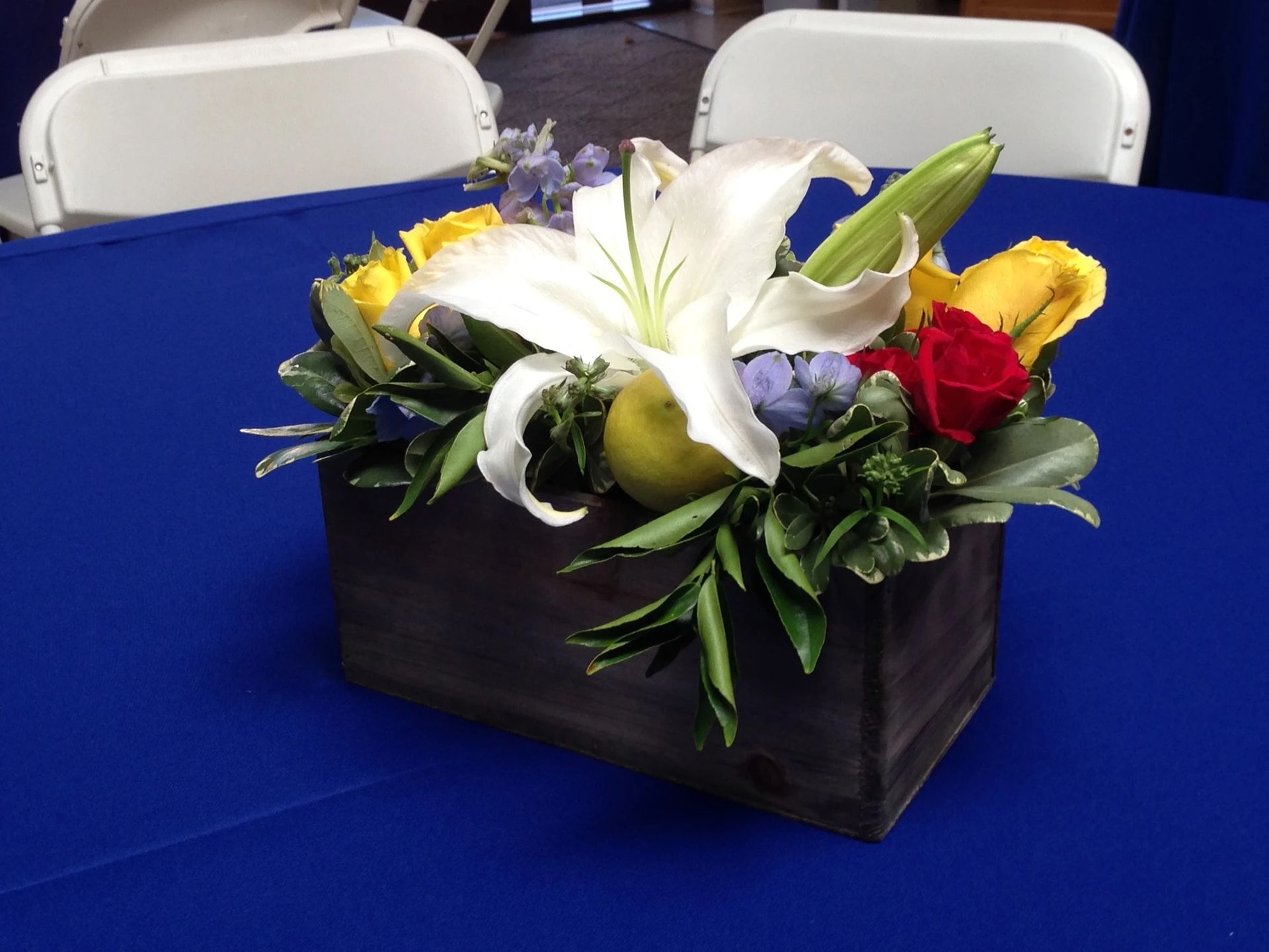 A wooden box filled with flowers sits on a blue table cloth