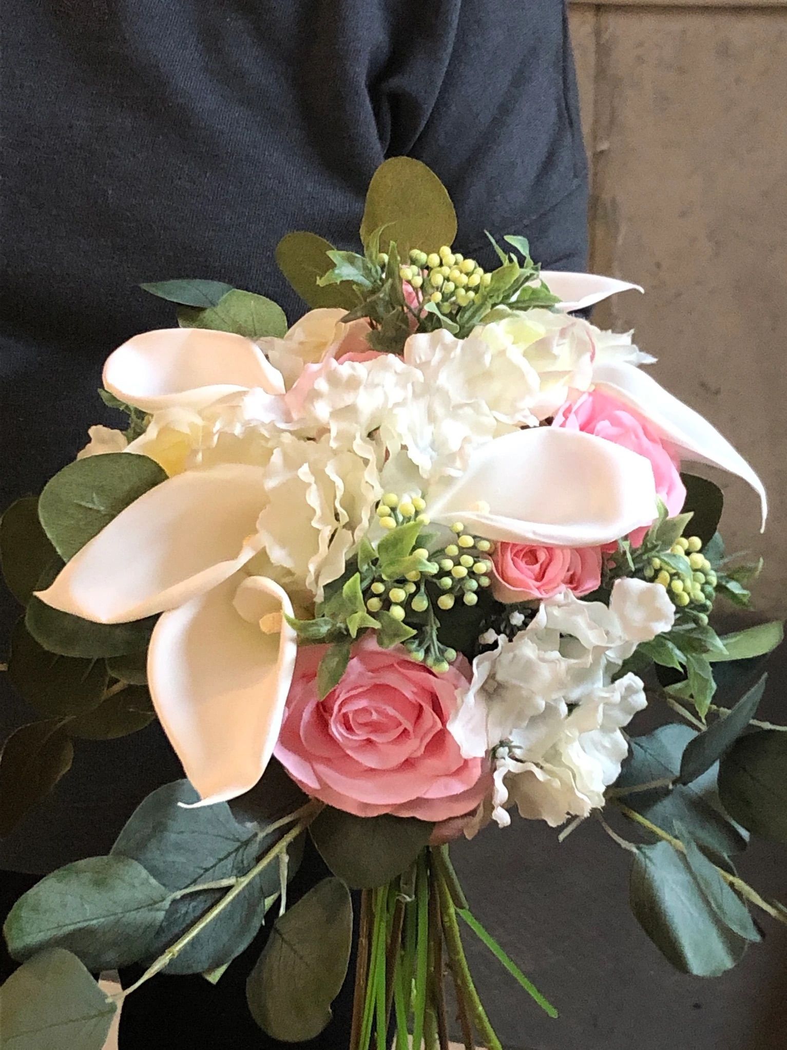 A person is holding a bouquet of pink and white flowers.
