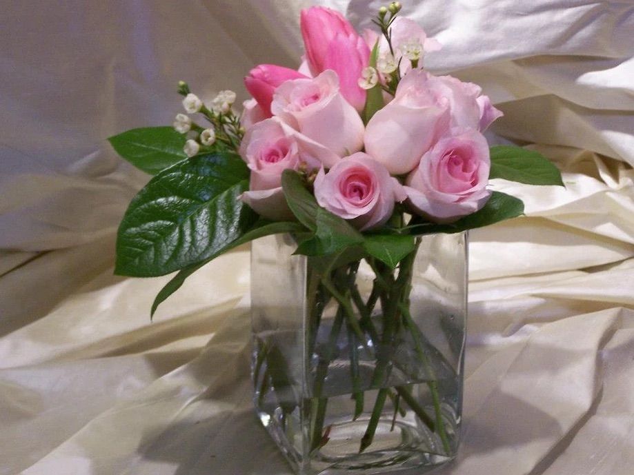 A vase filled with pink roses and lily of the valley