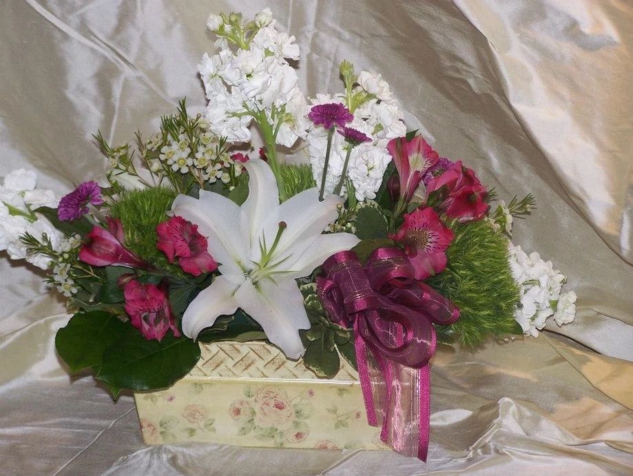 A white lily is surrounded by pink and white flowers