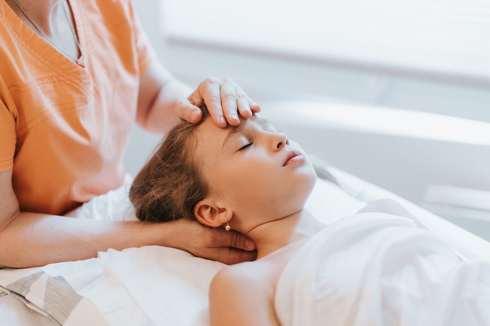 A woman is giving a child a head massage in a spa.