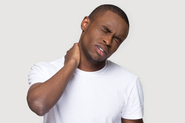 A man is holding his neck in pain.