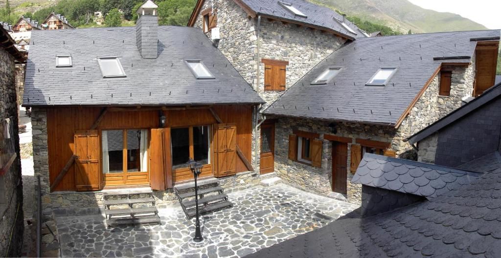 Cases de pedra amb persianes de fusta, teulades de pissarra i claraboies en un poble de muntanya.