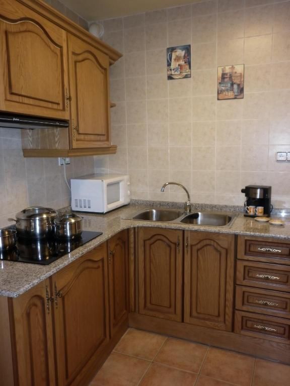 Cuina amb armaris de color marró clar, pica d'acer inoxidable i microones.