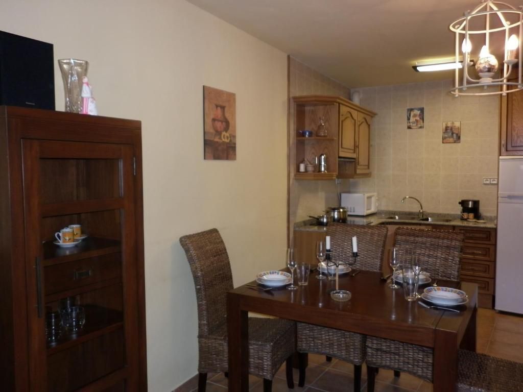 Menjador amb taula, cadires, armaris de cuina i un armari alt.