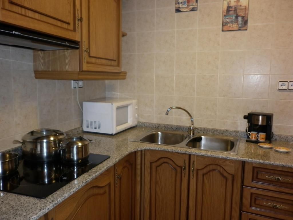 Cuina amb armaris de fusta, taulells de granit i pica, fogons i microones d'acer inoxidable.