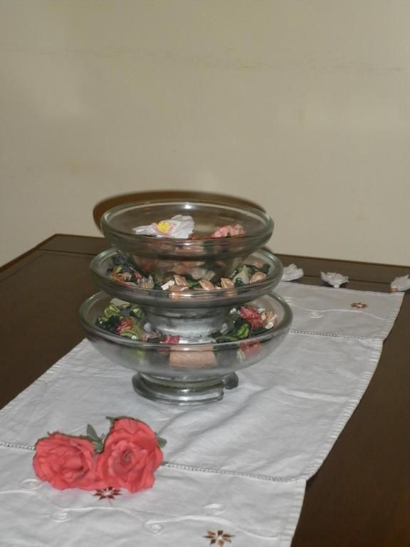 Bols de vidre apilats amb potpurri sobre una passarel·la blanca, roses vermelles.