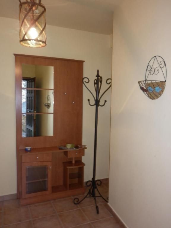 Entrada amb armari de fusta, mirall, penja-robes i cistella penjant. Tons càlids, terra de rajoles.