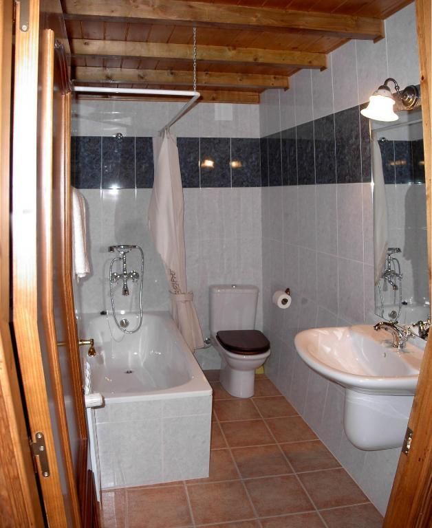 Bany amb banyera, vàter, lavabo i parets i terres de rajoles, vist des d'una porta.