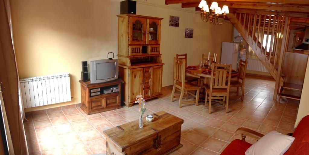 Sala d'estar amb mobles de fusta, taula de menjador, escales i sofà vermell.