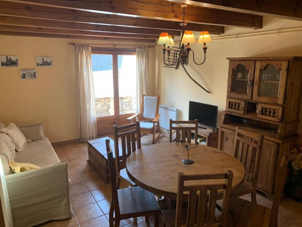 Sala d'estar amb mobles de fusta, incloent-hi una taula de menjador, un armari i un sofà. Estètica rústica i lluminosa.