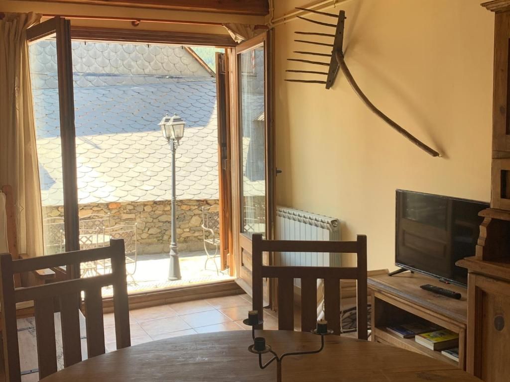 Interior amb vistes al balcó, taula i cadires de fusta, televisió, rasclet decoratiu, parets beix.