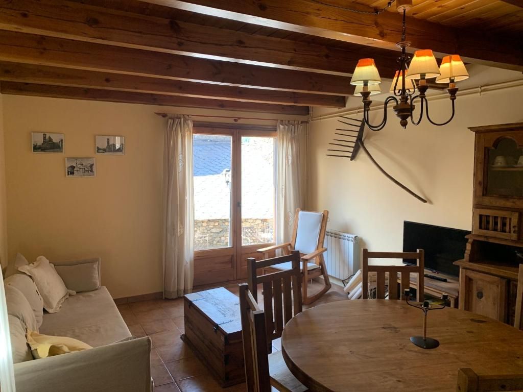 Sala d'estar amb bigues de fusta, taula rodona, sofà i finestra.