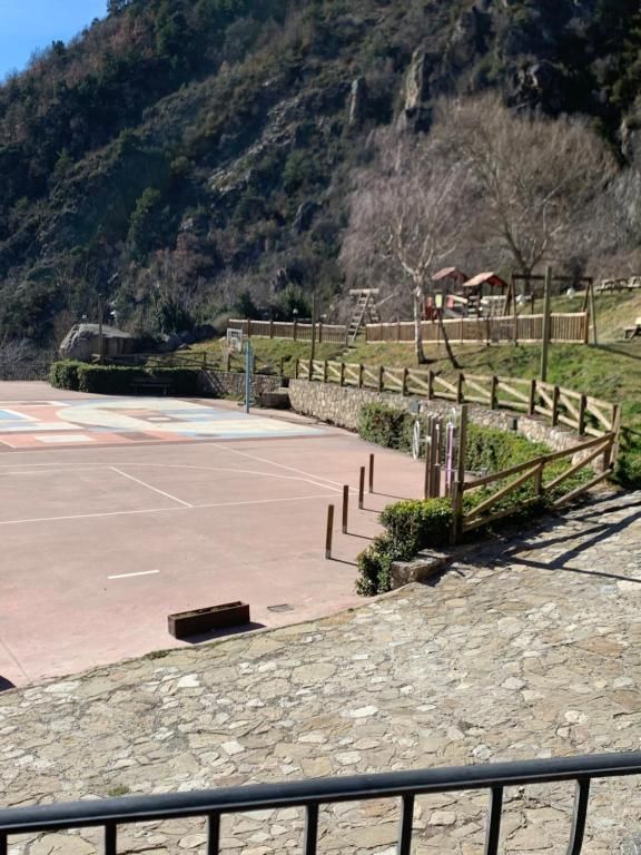 Pista de bàsquet en un parc, amb una tanca de fusta i muntanyes de fons.