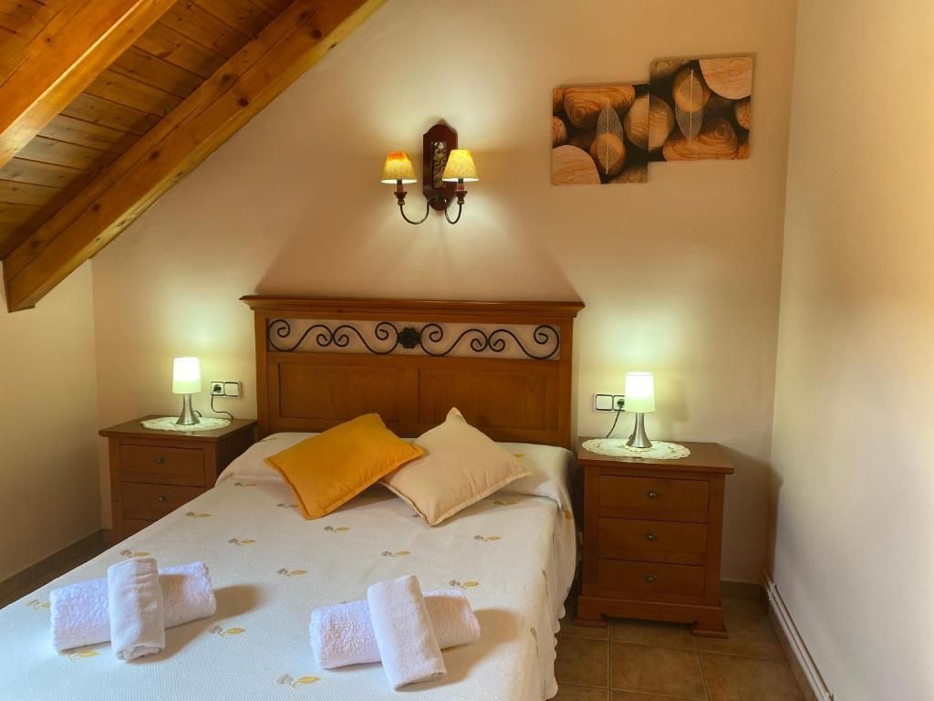 Dormitori amb llit, tauletes de nit, làmpades i art decoratiu a la paret.