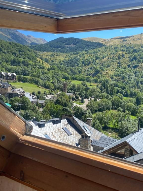 Vista des d'una finestra d'un poble situat en una exuberant vall verda amb muntanyes.