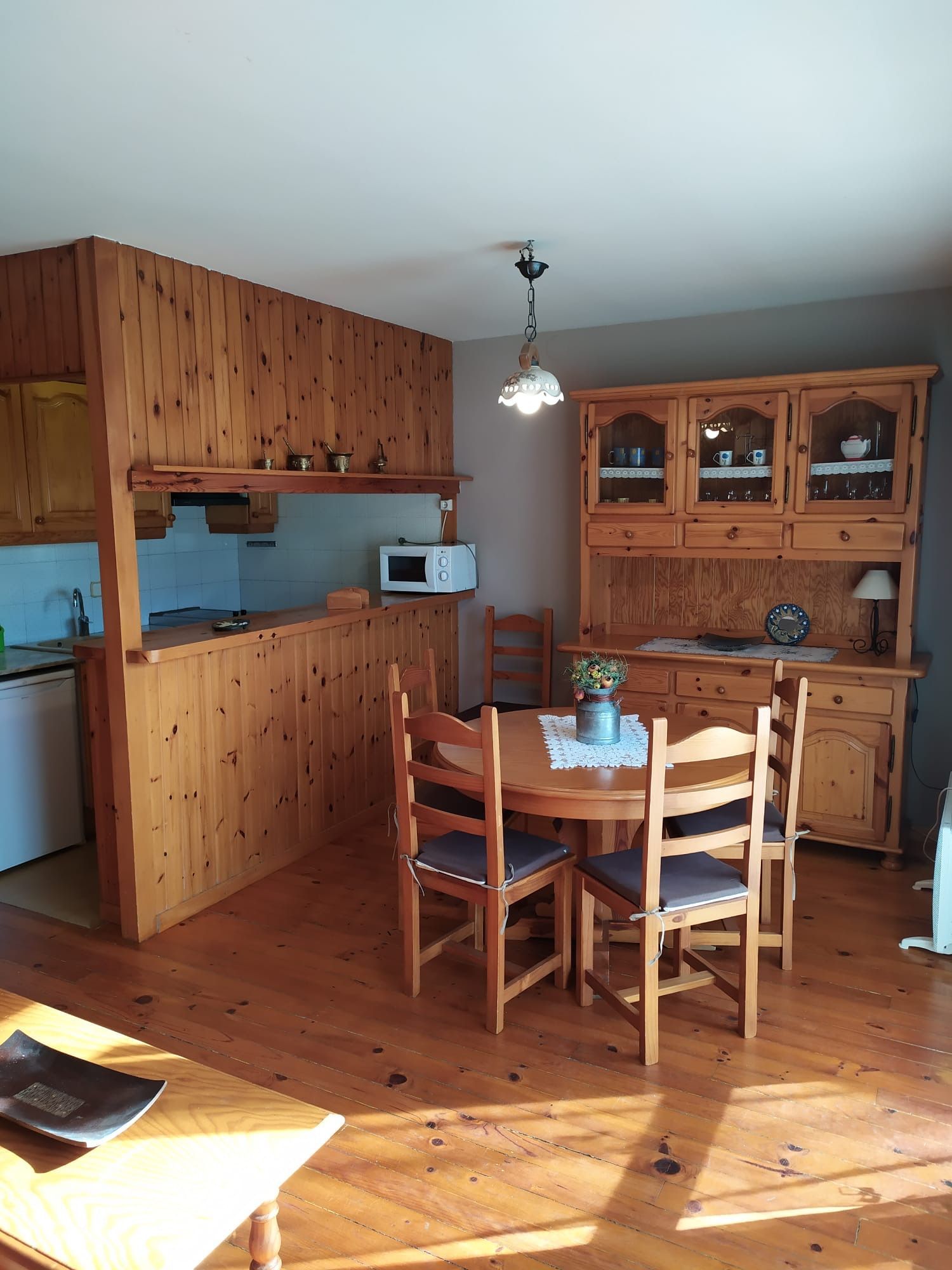 Cuina i menjador de fusta amb taula rodona i aparador.