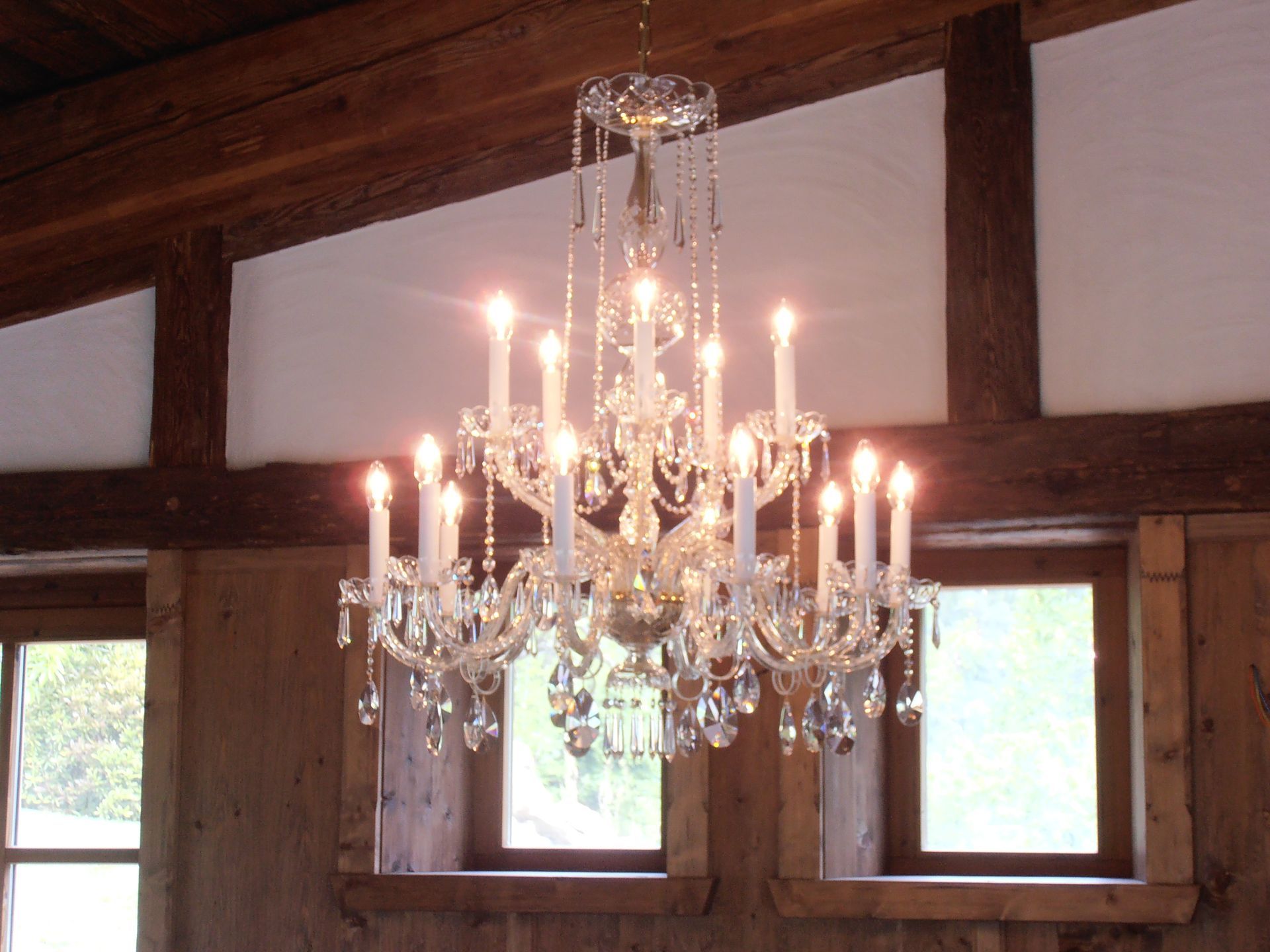 ein Kronleuchter mit vielen Kerzen hängt an einer Holzdecke