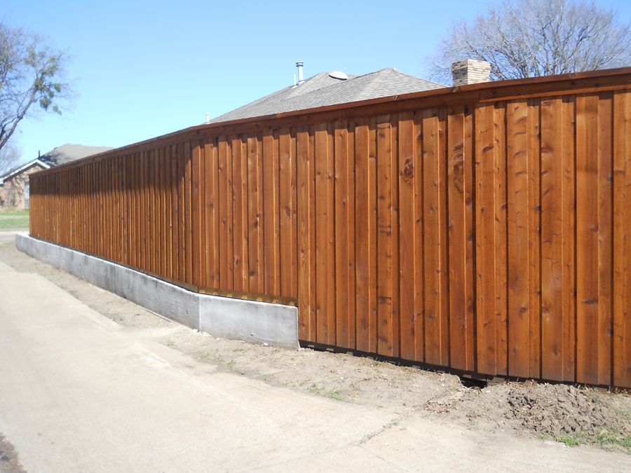 A wooden fence is along the side of a road