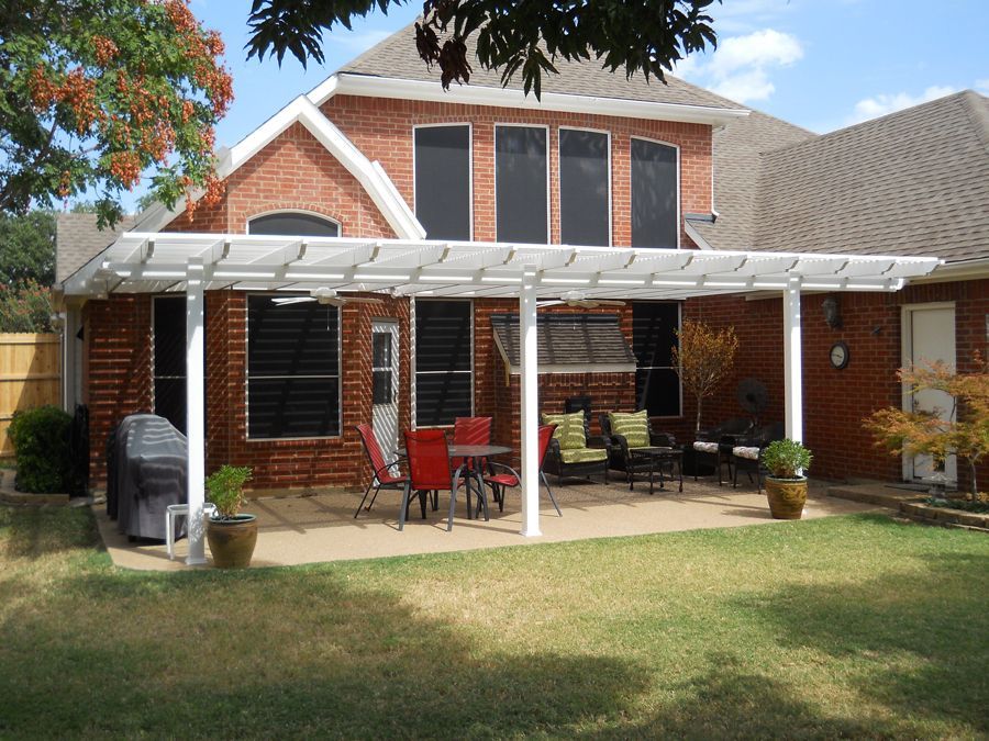 A brick house with a white pergola in the backyard